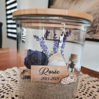 Création florale funéraire avec rose éternelle, sable naturel et plaquette de bois gravée en souvenir d’un animal