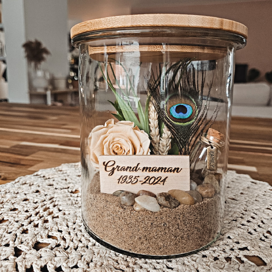 Souvenir floral significatif avec lume de paon et rose éternelle, créé pour honorer une grand-maman