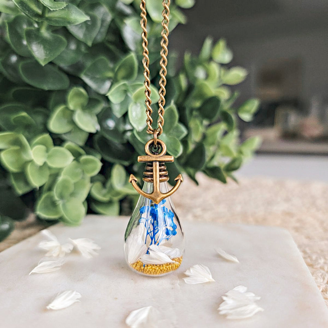 Pendentif ancre avec fleurs séchées bleues et blanches – bijou symbolique à offrir en souvenir ou pour un moment fort