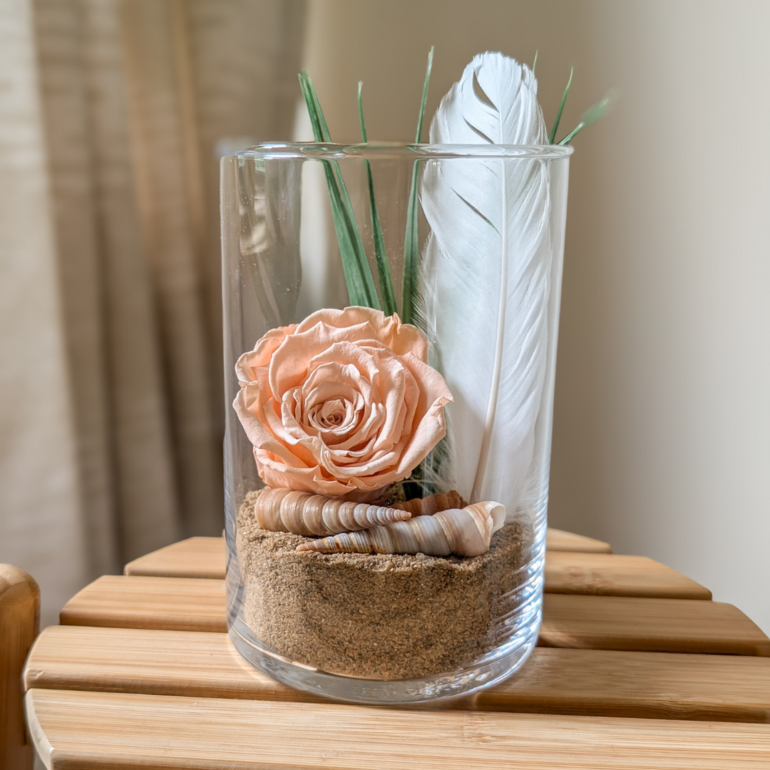 Arrangement floral fait main, avec une plume blanche et des coquillages.