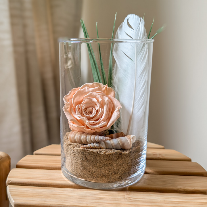 Arrangement floral fait main, avec une plume blanche et des coquillages.