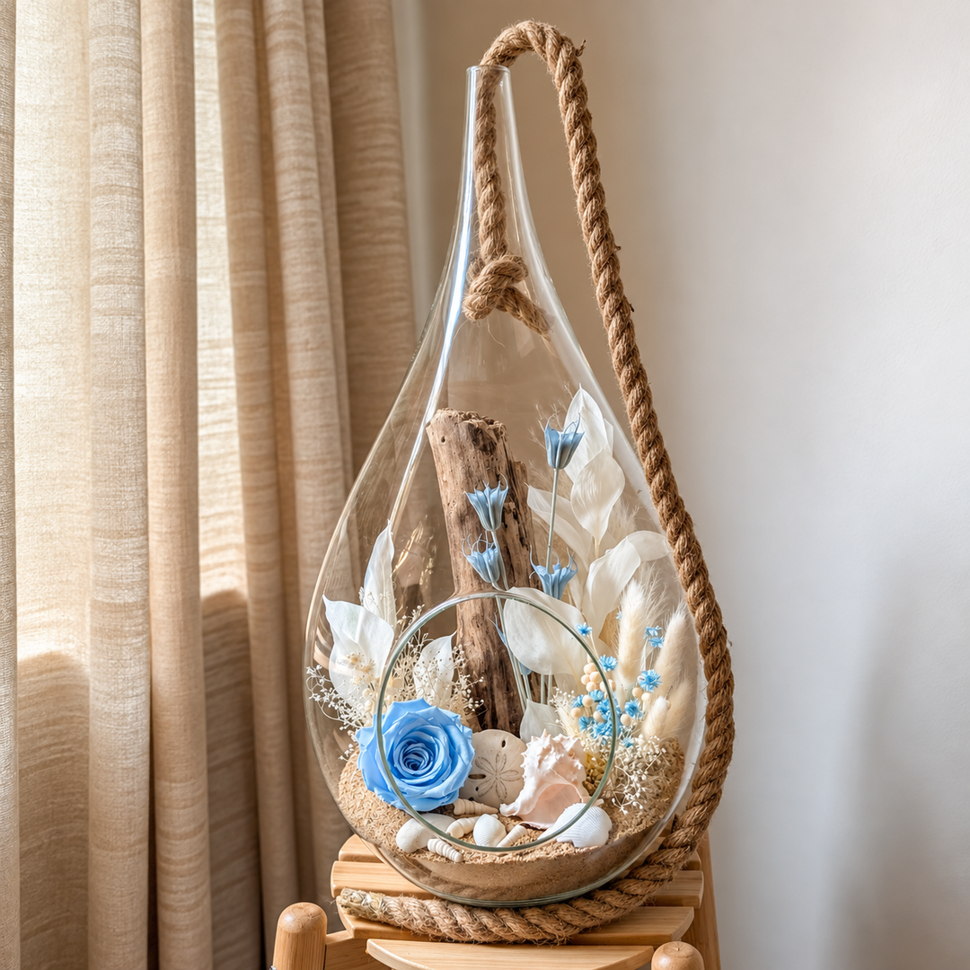 Arrangement floral avec rose éternelle bleue, fleurs séchées, bois flotté et coquillages