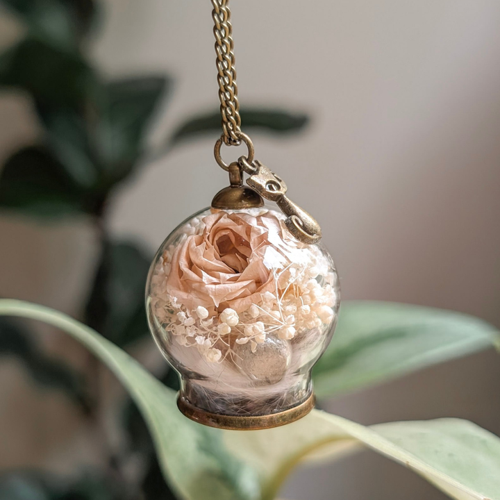 Bijou commémoratif réunissant poils et cendres d’un chat dans un globe de verre avec rose éternelle rose pâle