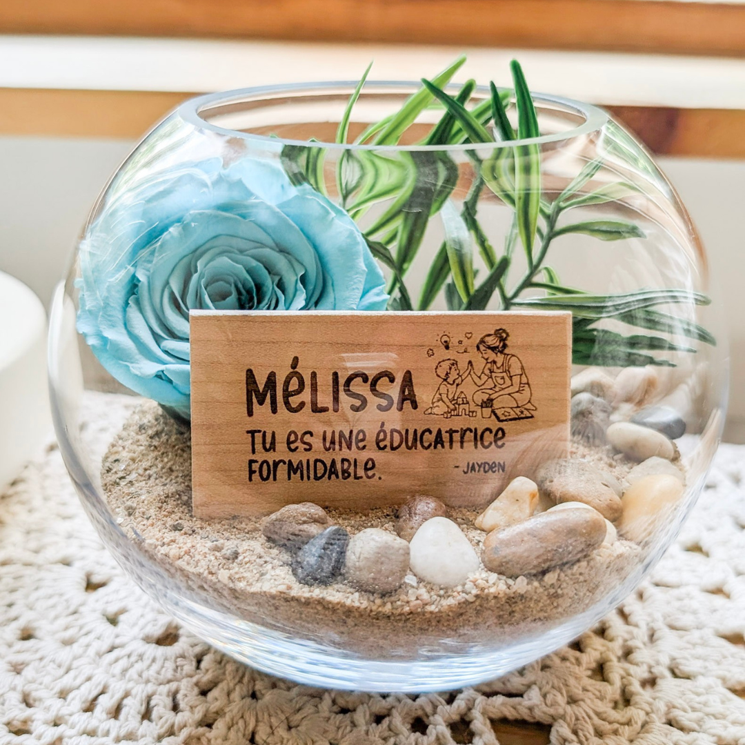 Arrangement floral avec rose éternelle turquoise et plaquette de bois gravée, un cadeau personnalisé pour éducatrice.