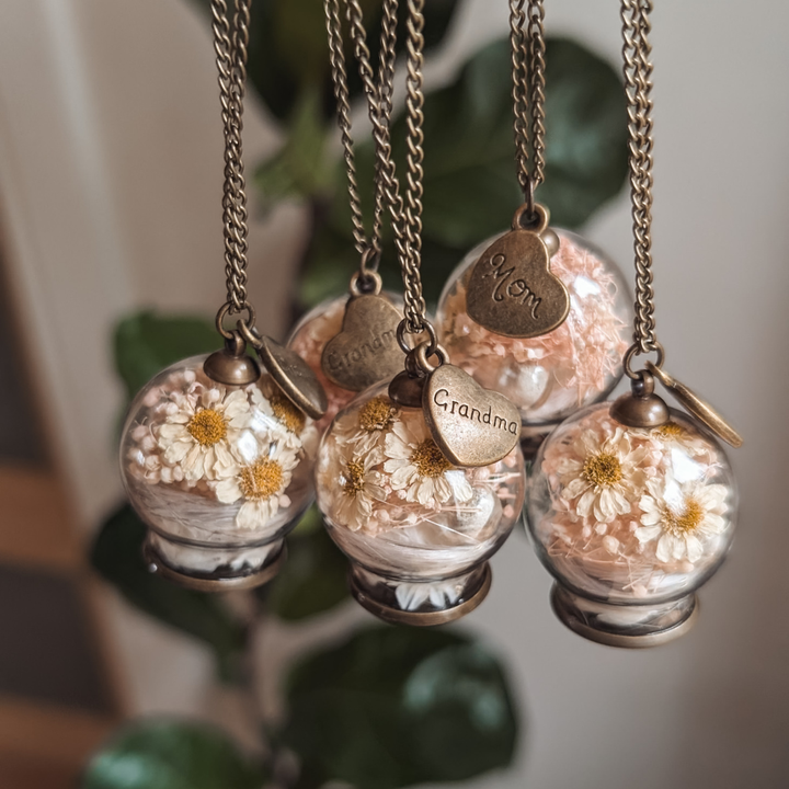 Cinq colliers souvenir en globe de verre, chacun avec une mèche de cheveux, des marguerites et une breloque cœur Mom ou Grandma