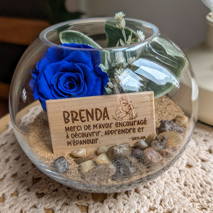 Création avec rose éternelle bleue et dessin personnalisé gravé sur une plaquette de bois, à offrir à une éducatrice.
