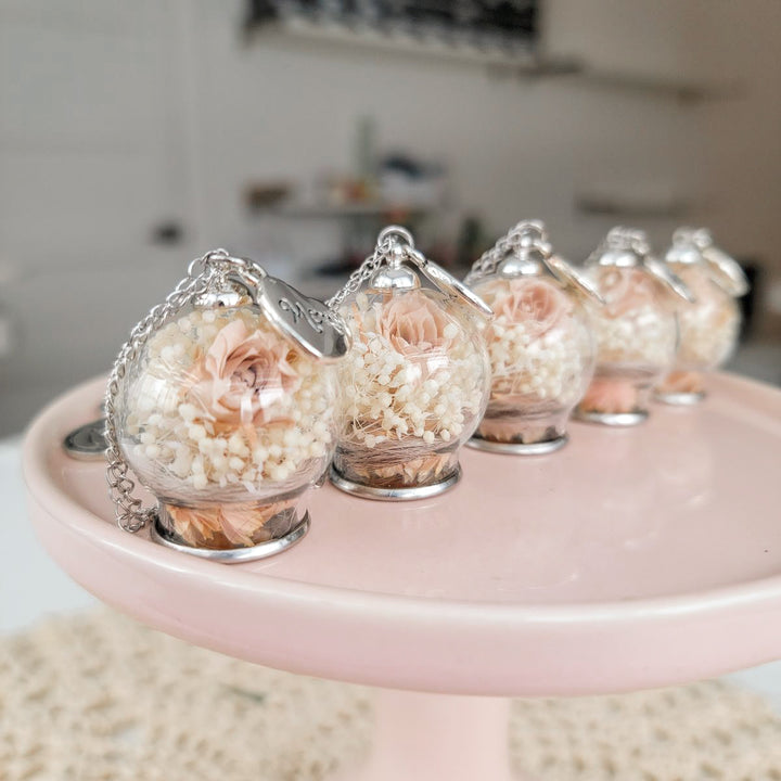 Pendentif mémoire avec mèche de cheveux, fleurs blanches et chaîne en acier inoxydable.