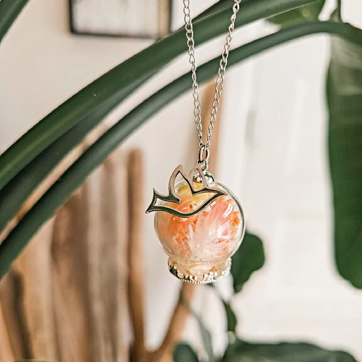 Bijou commémoratif pour oiseau composé d’une sphère en verre avec plume orange, breloque d’oiseau et chaîne en acier inoxydable.