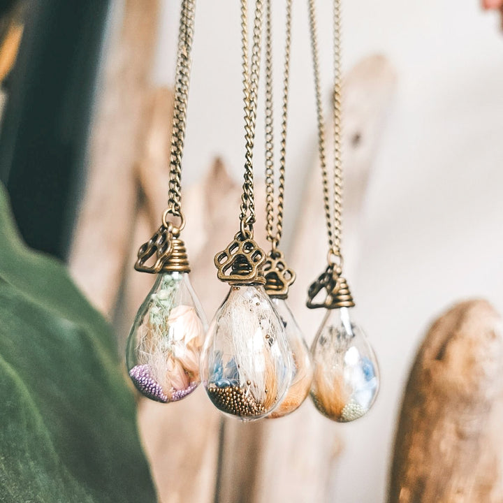 Quatre pendentifs en bronze antique avec poils d’animaux et fleurs de gypsophiles mauves, bleues et blanches